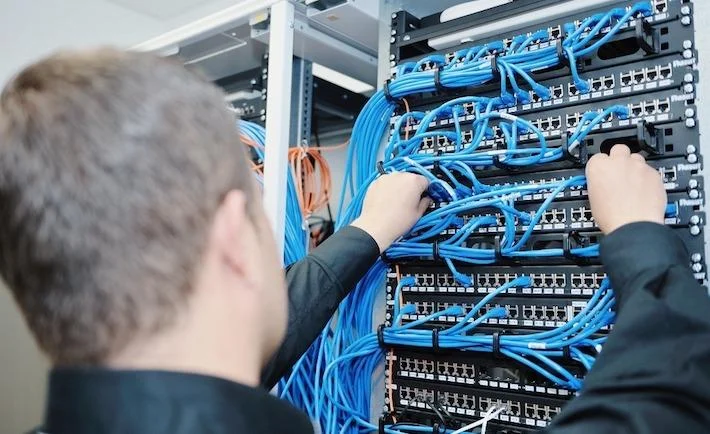 Técnico trabajando en un gabinete de red con cableado estructurado